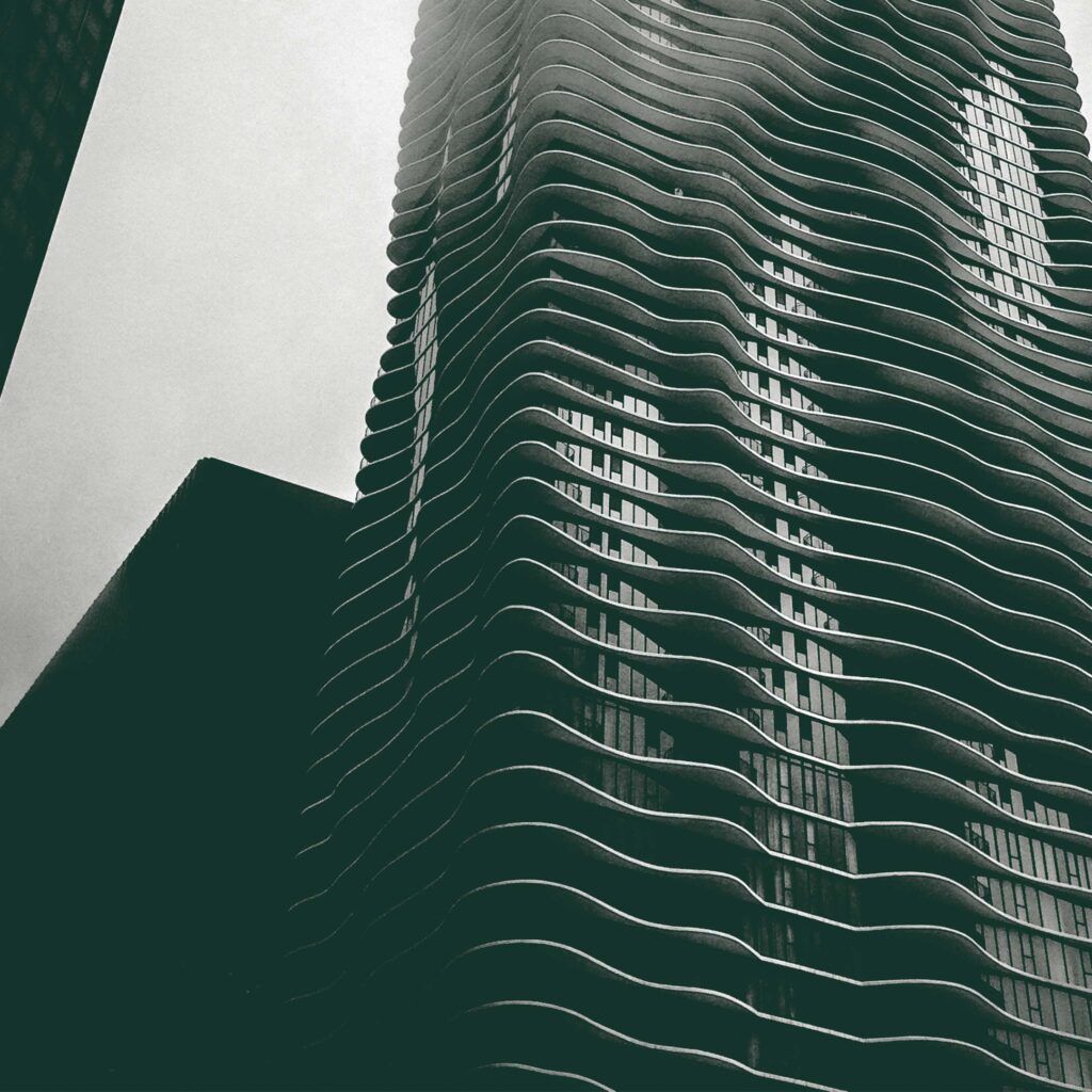 Upward view of a contemporary high-rise building with wave-like architectural design, emphasizing modern urban construction and engineering.